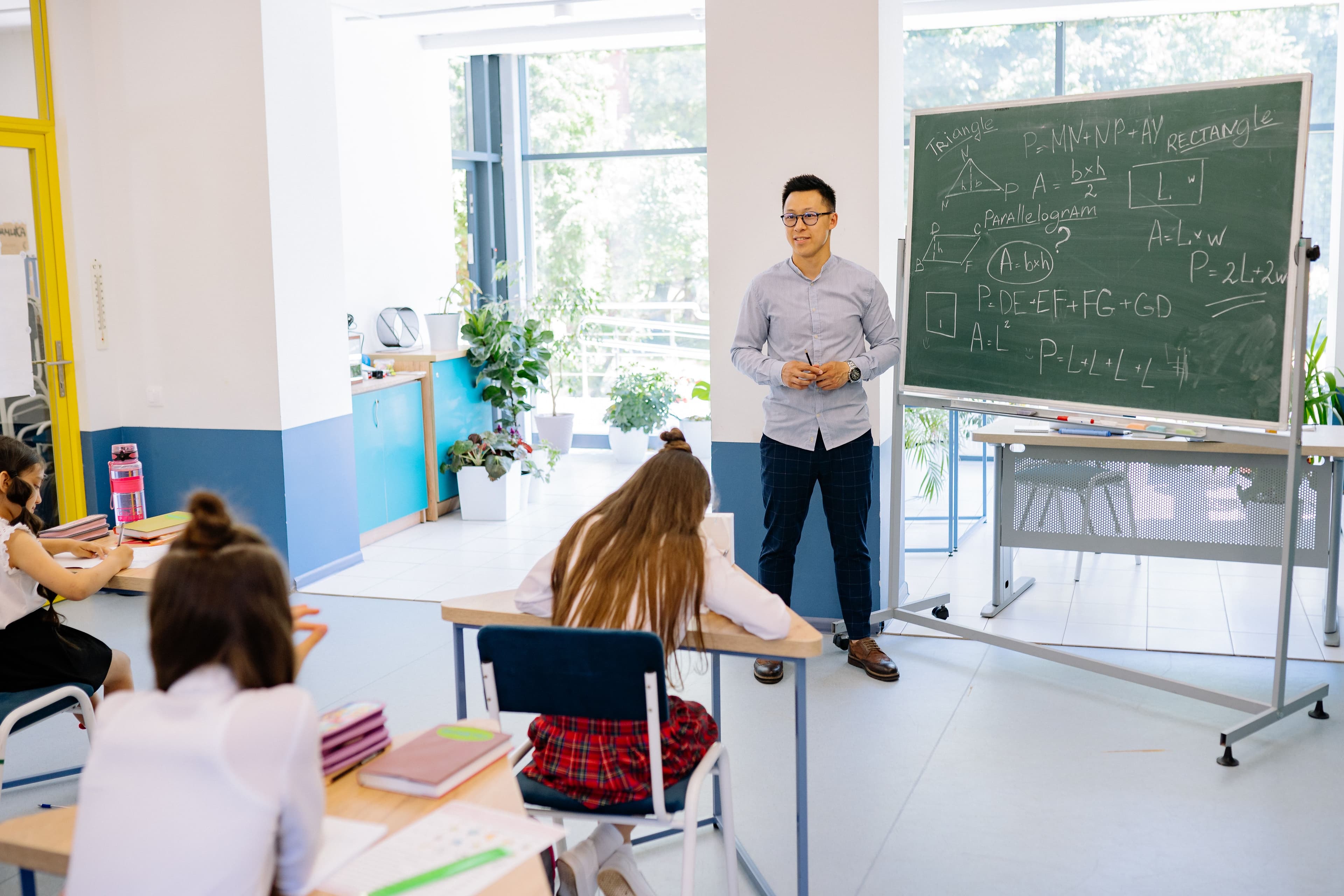 Teacher at chalkboard with maths formulas